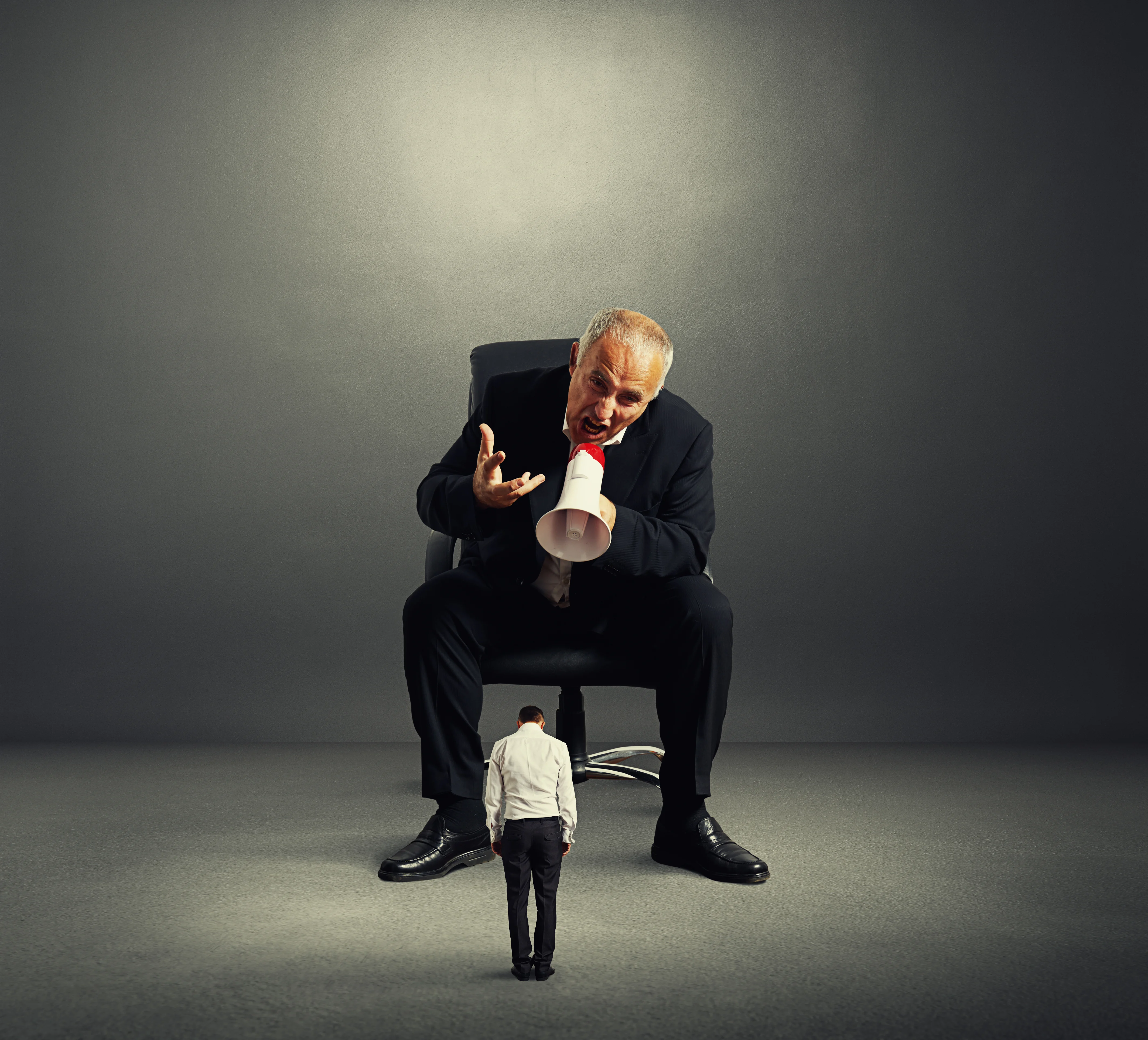 One large person is yelling at a small person through a megaphone