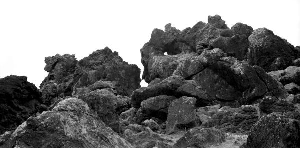 Black and white photograph of a hilly outcropping in front of a white sky.