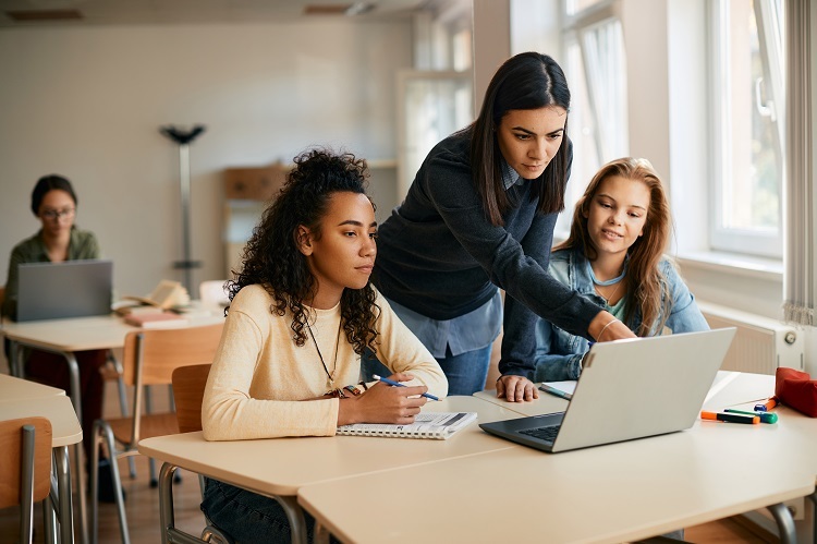 Teacher and students looking at a computer. 