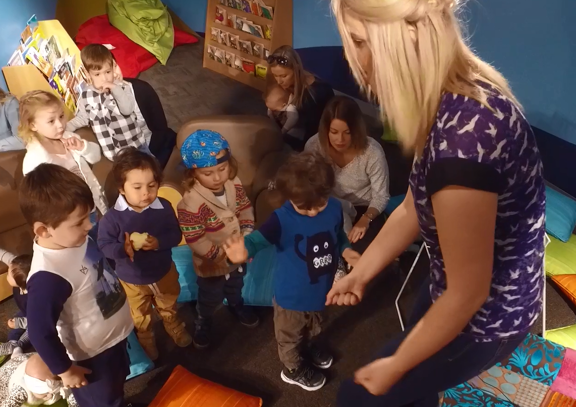 photograph of an educator reading to children while standing up and moving