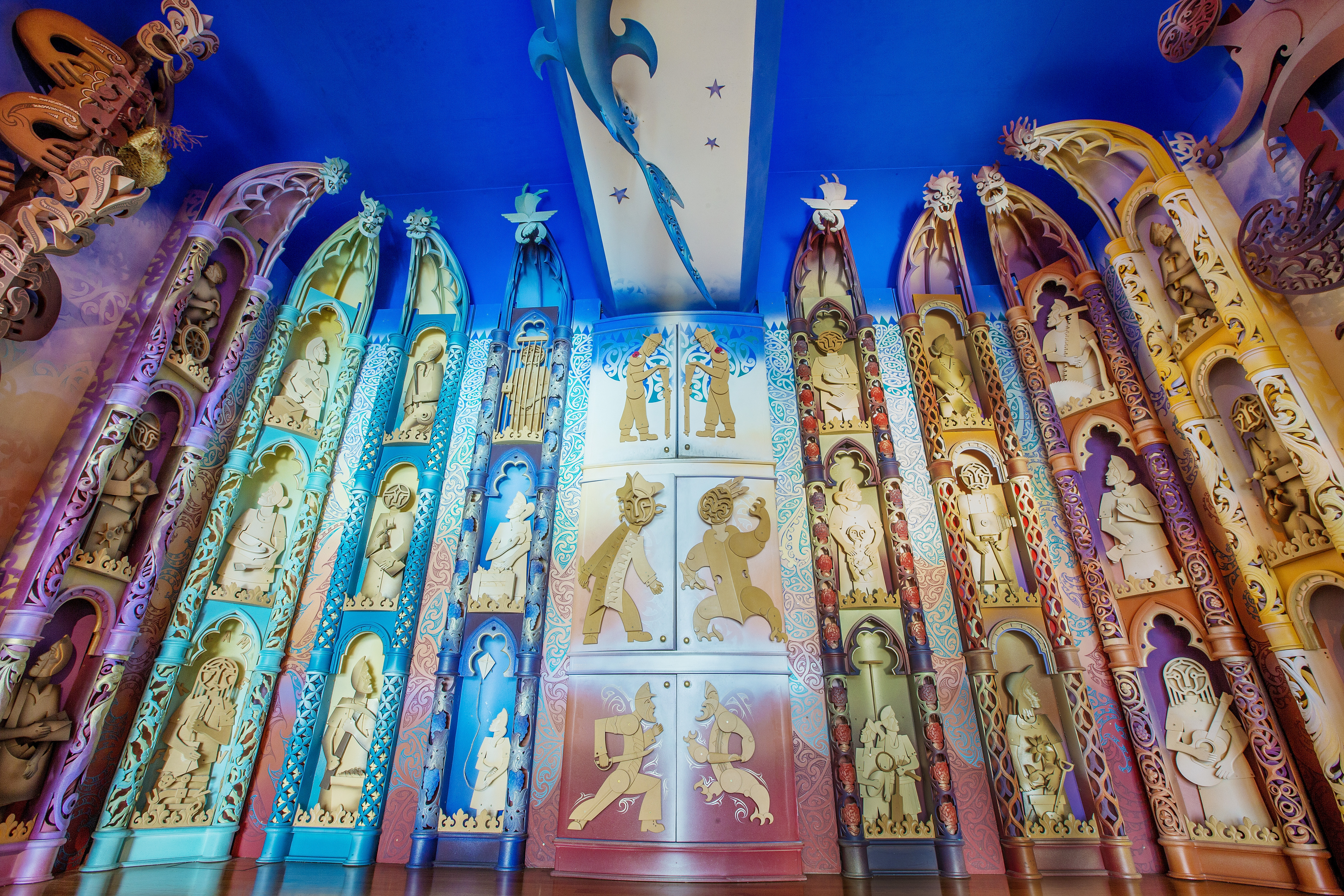 A very detailed set of carvings of many figures, a rainbow of soft colours are used, and the arched pockets speak to holiness. A stylized shark swims at the ceiling panel.