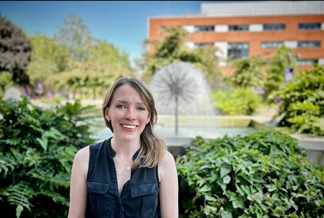 Photo of Dr Louise Nuttall stood in front of a fountain in the style of a dandelion.