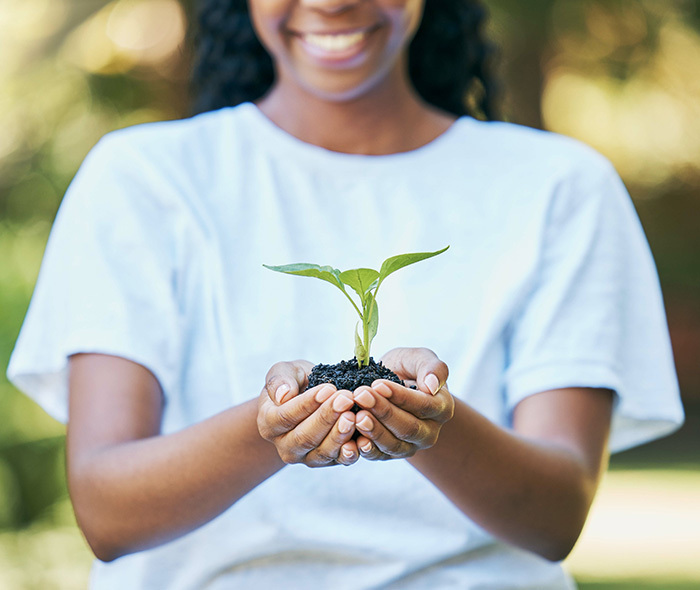 A black youth holding a seedling and smiling.