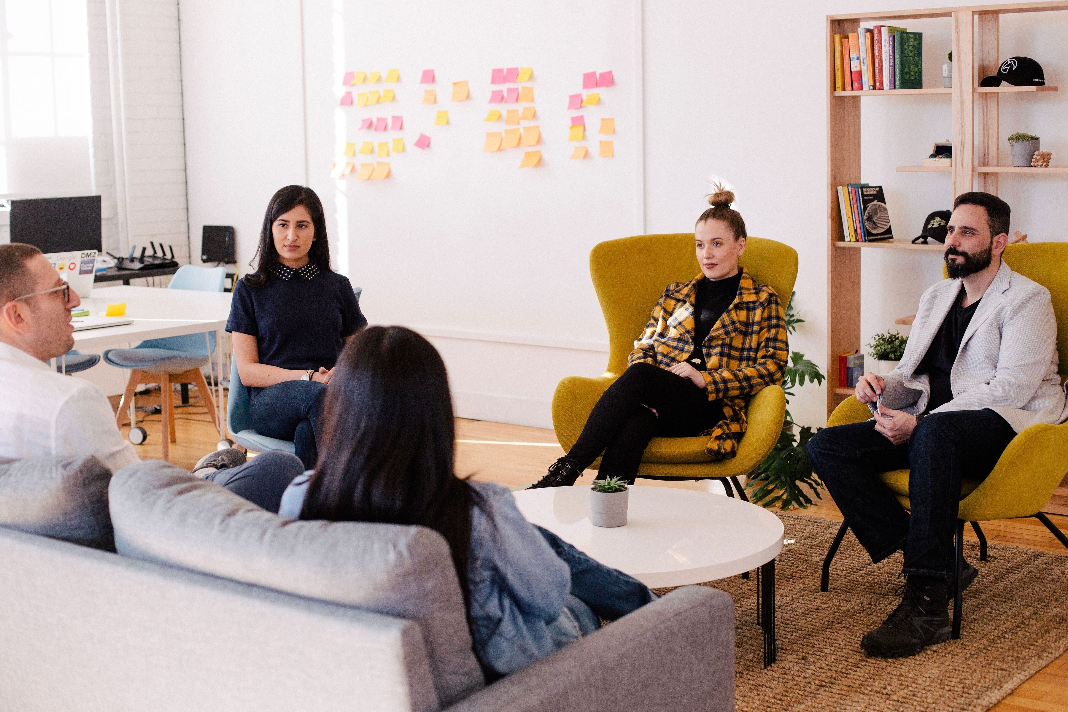 Image of a team sitting together and discussing with post-its in the background