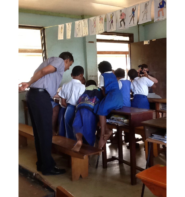 Vinesh Chandra atrae a estudiantes zambianos descalzos en un aula de madera tradicional