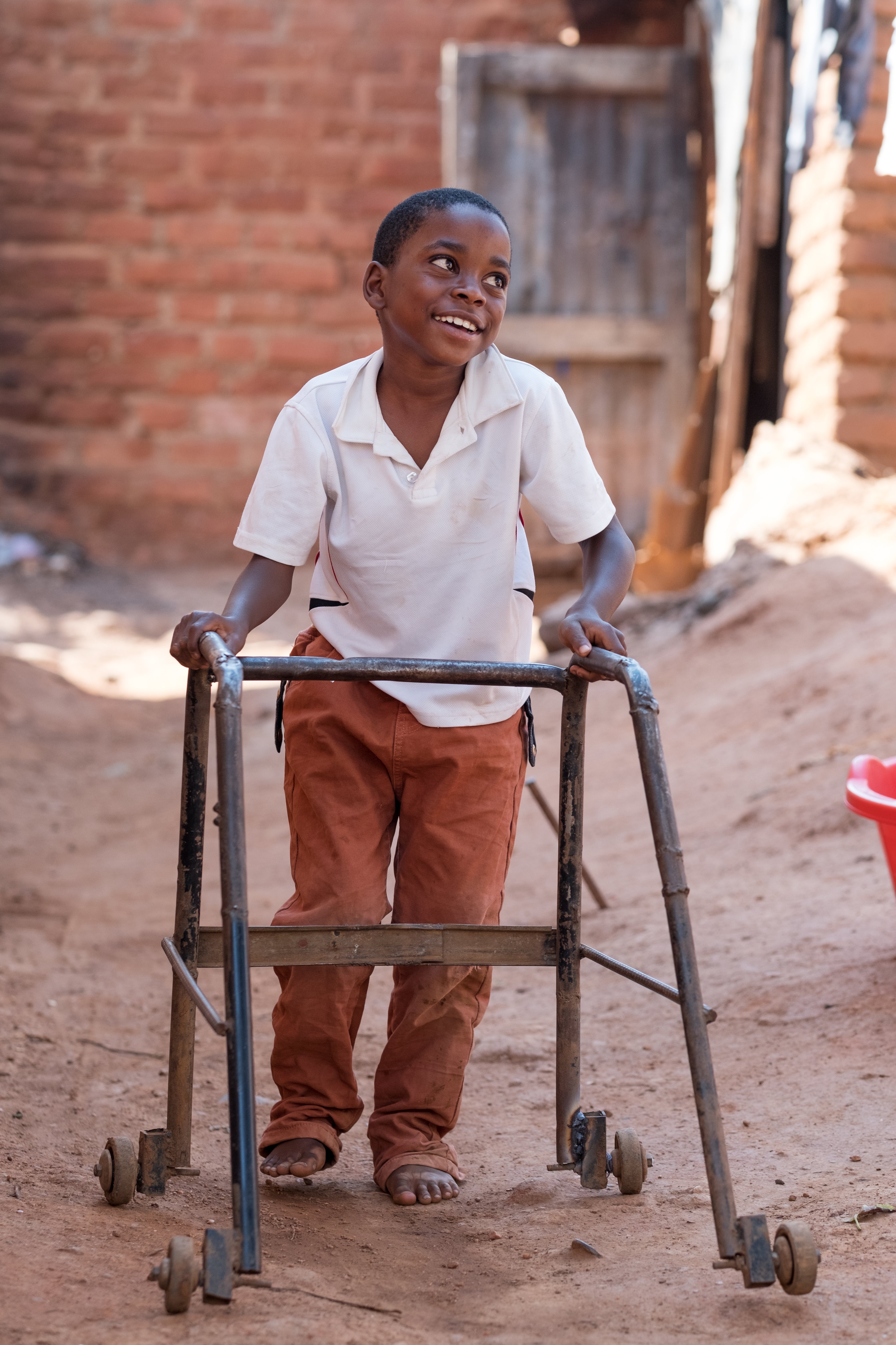 A young boy walking with support from a walking frame