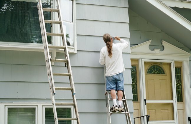 Contractor painting exterior of house.