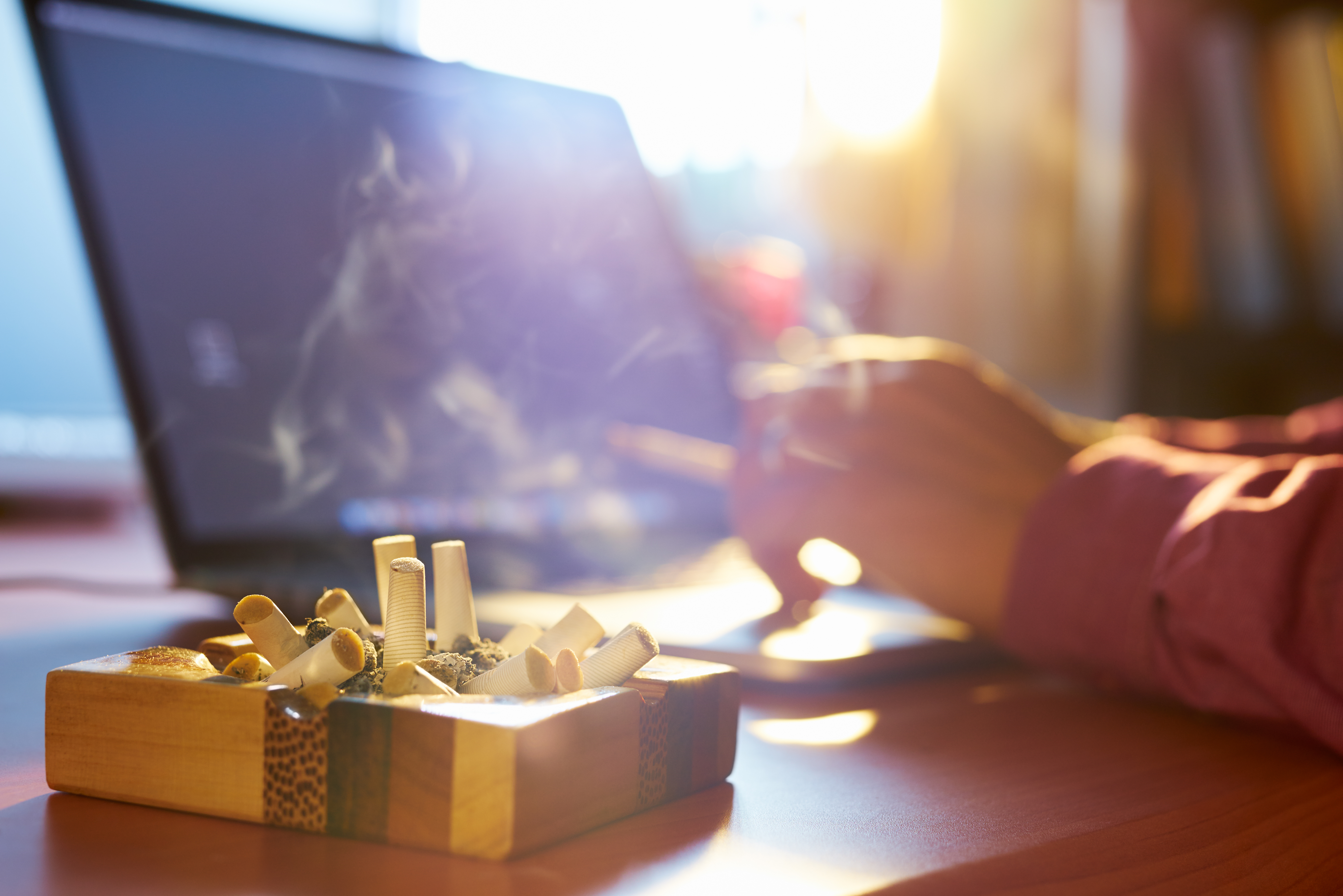 Smoking worker in an office, an ashtray with sigarette butts on the desk