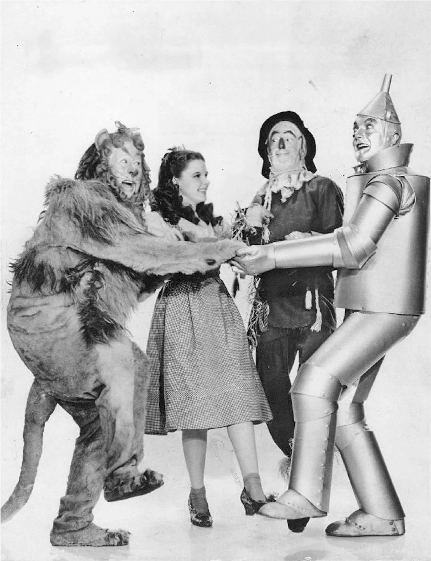 4 Wizard of Oz characters dancing while holding hands