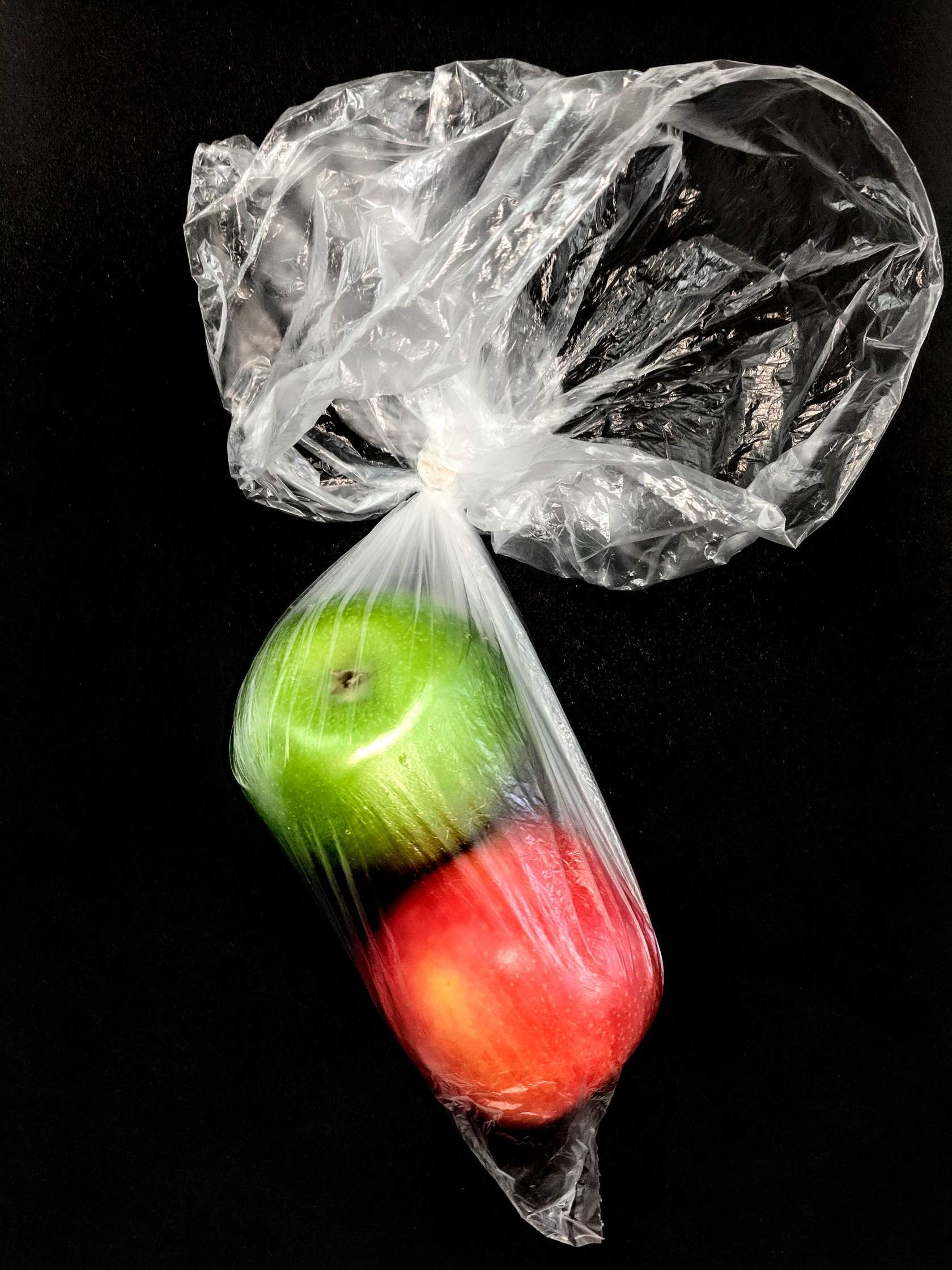 A green and a red apple in a clear plastic bag