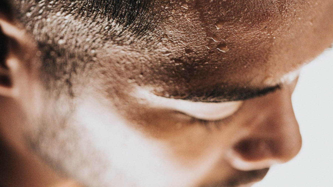 close up of a person's eyes and forehead with sweat beading across their brow