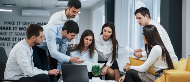 A collection of learners gathered around a laptop