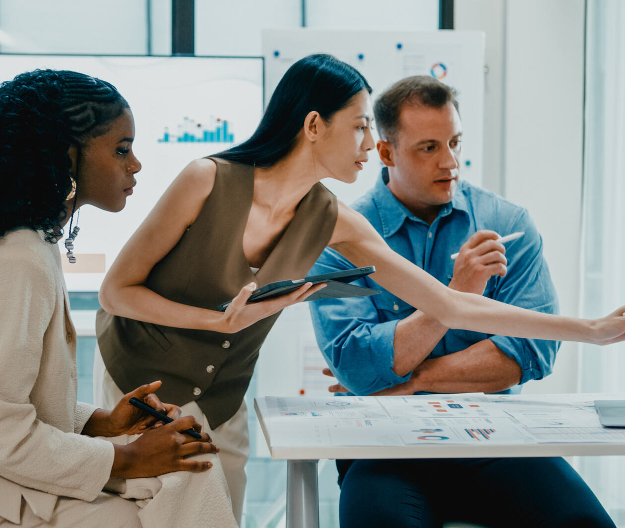 two women and a male colleague look at the same screen showing data