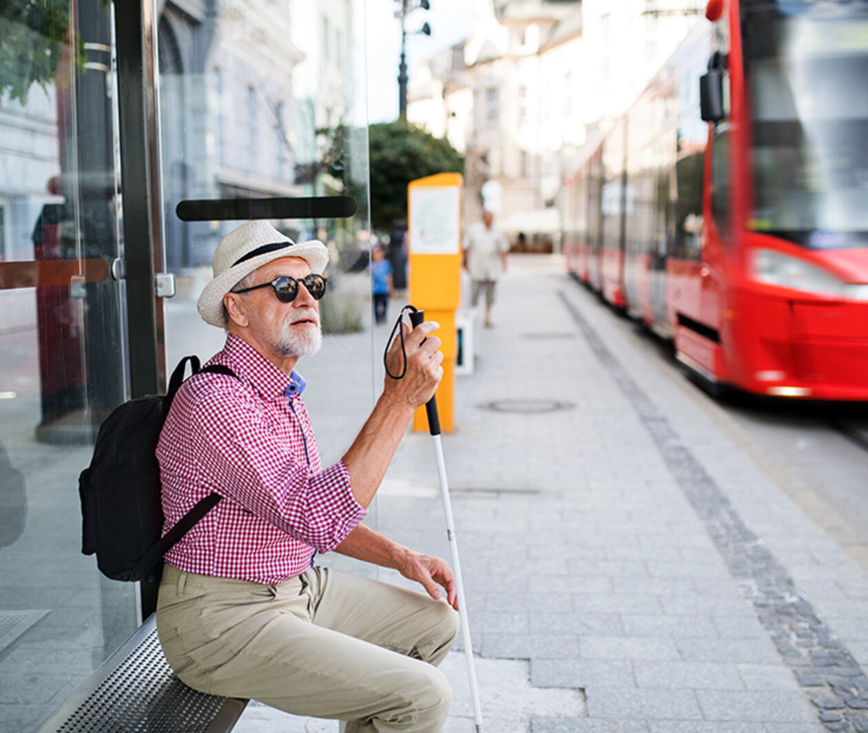 Older man with vision impairment waits for a tram