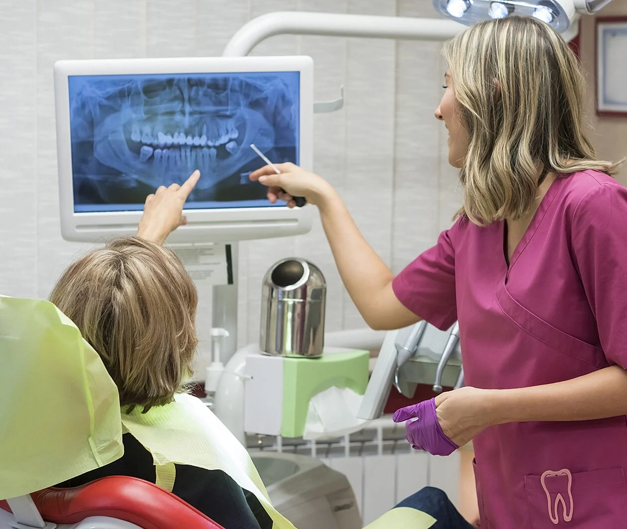 Dental professional looks at an xray image on screen with a patient