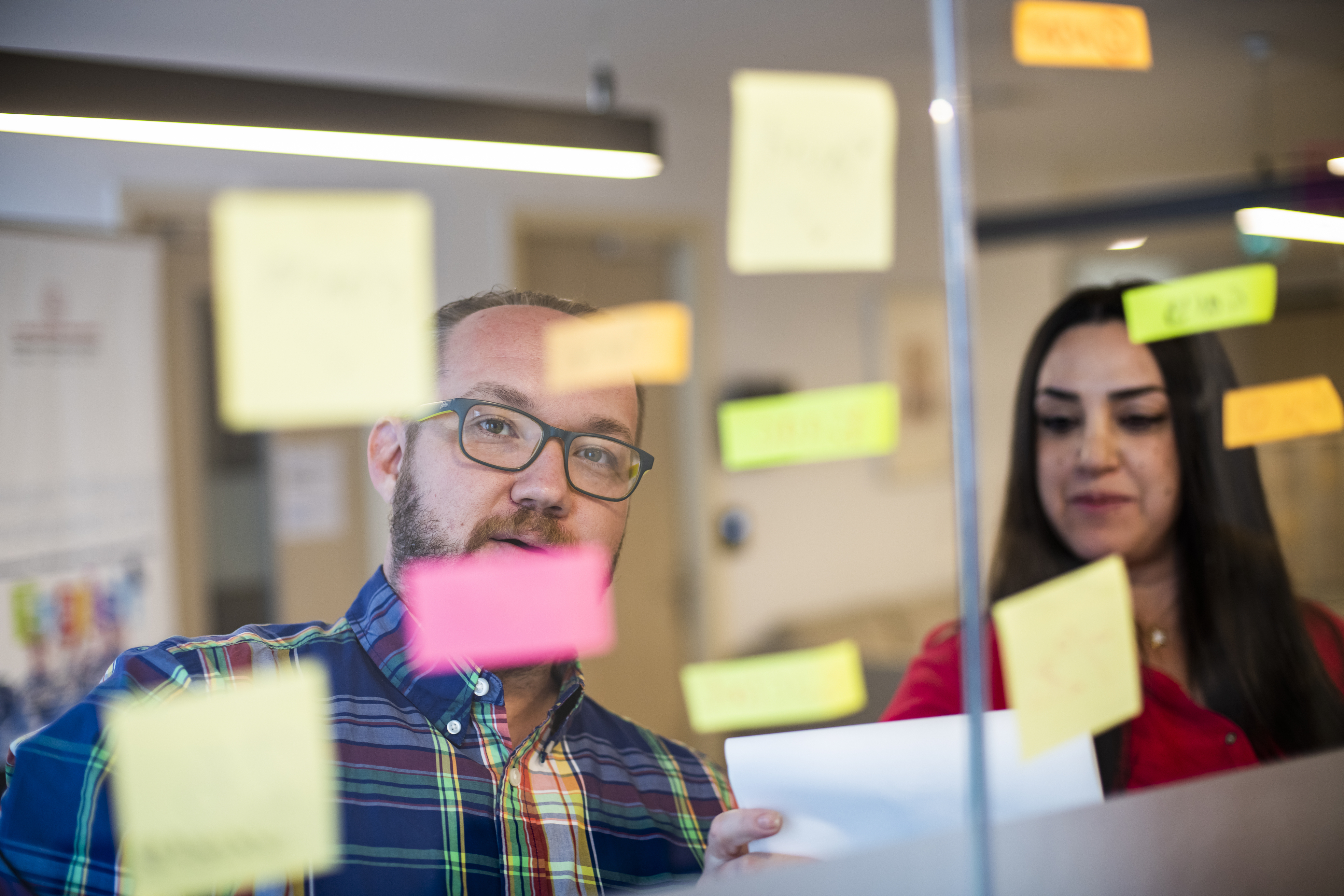 Two teachers looking at a board with coloured sticky notes.