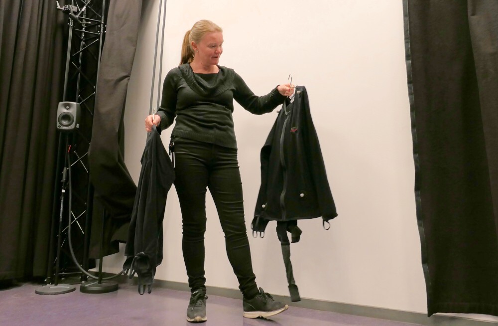 Woman holding two motion capture suits.