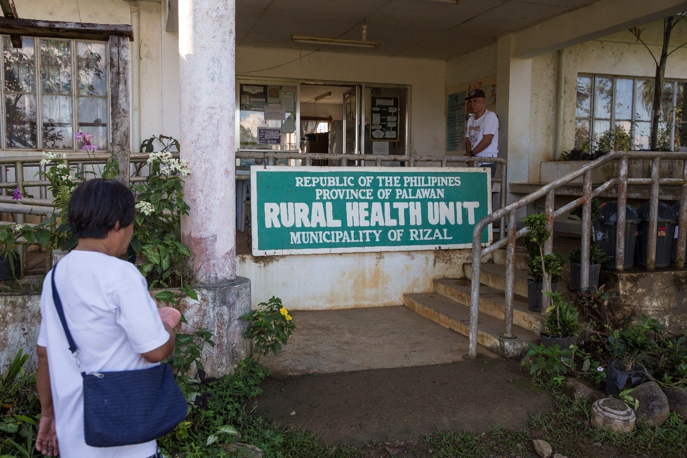 A woman is about to visit walk up the steps to a rural health unit in Philippines