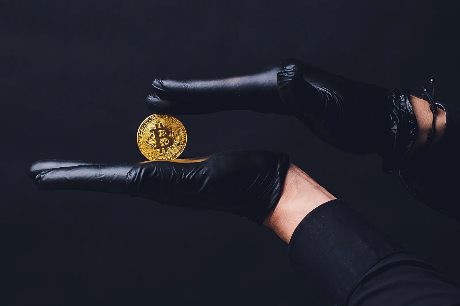 Gloved hands holding a coin that represents Bitcoin.