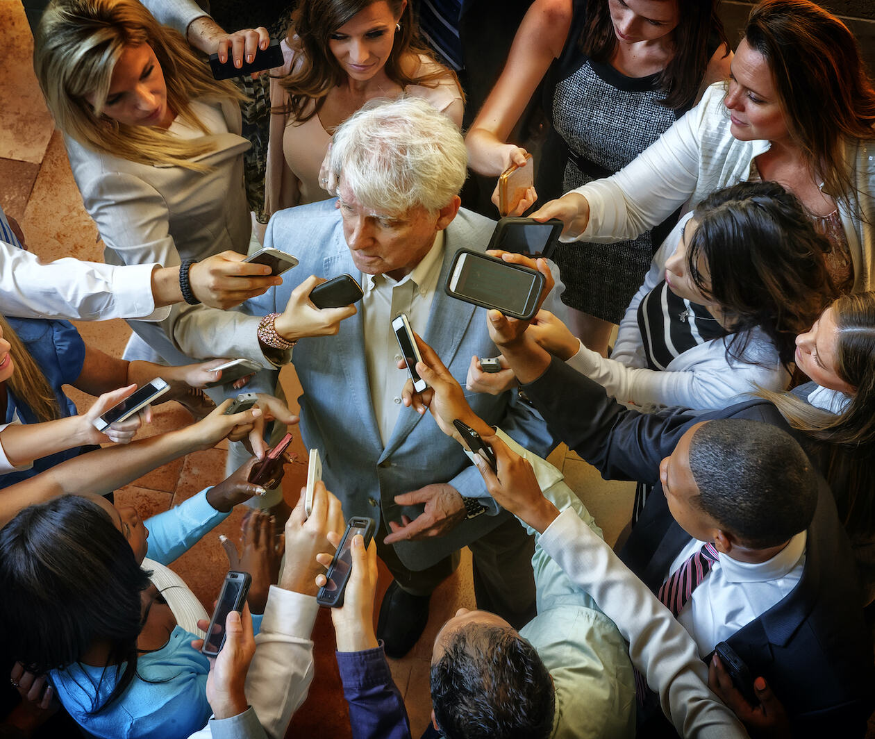 Man surrounded by journalists with microphones