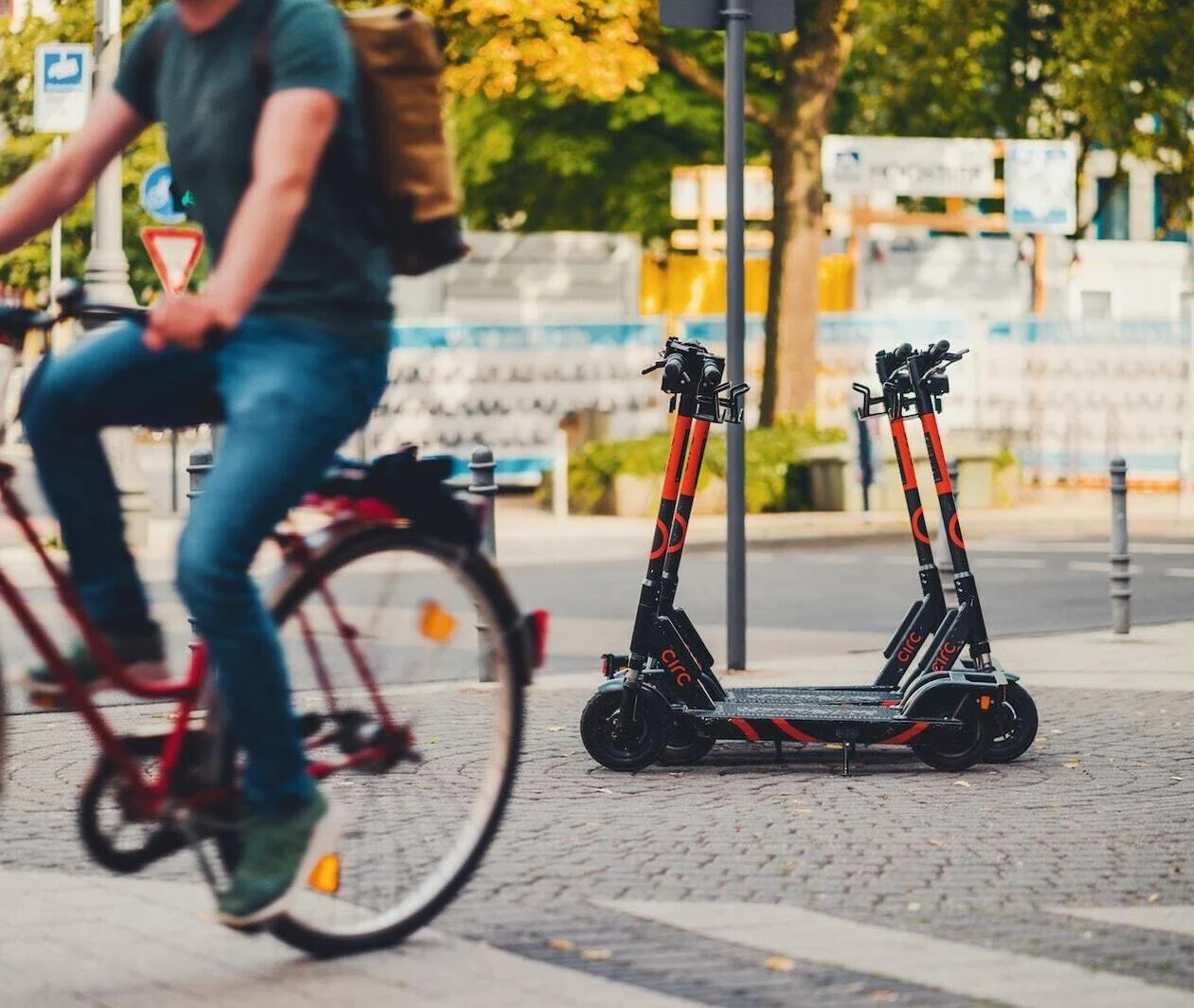 Parked electric scooters with a bicycle riding by