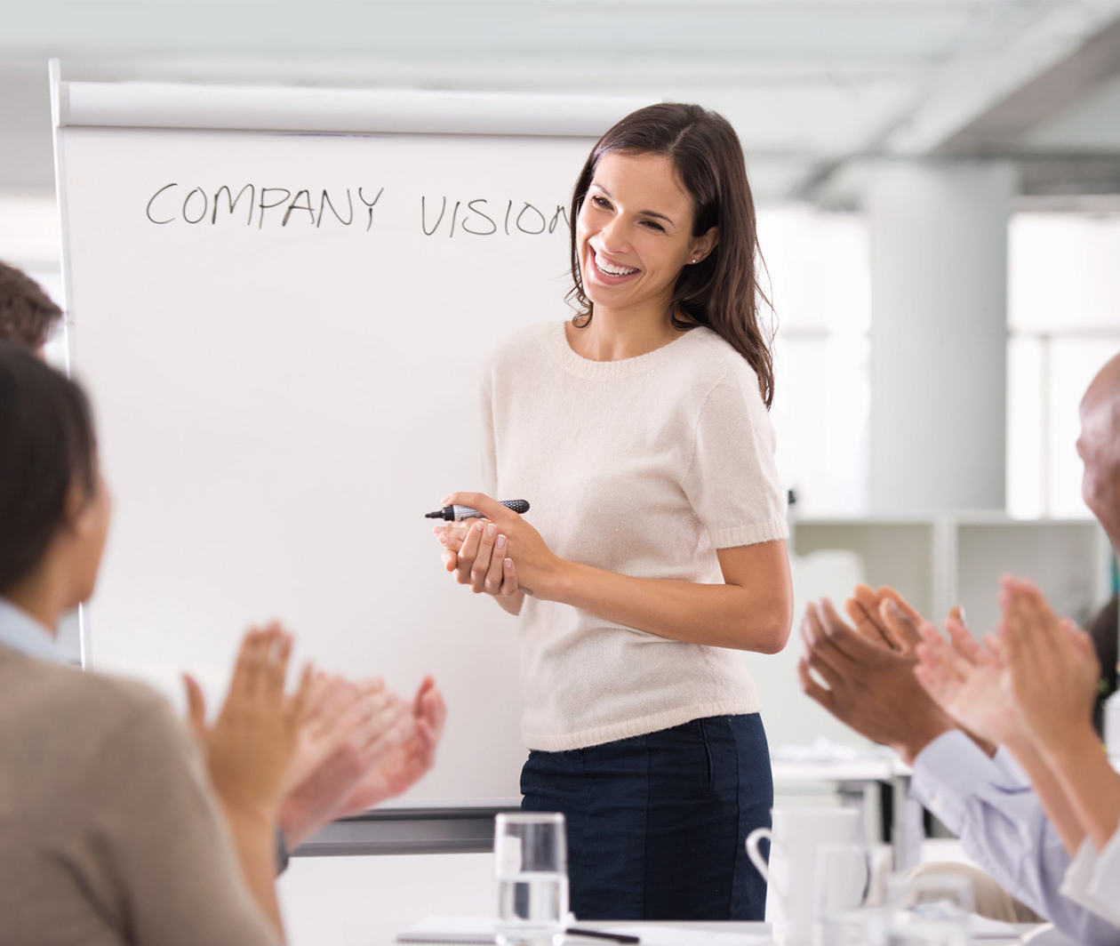 Business woman smiling and standing at a white board