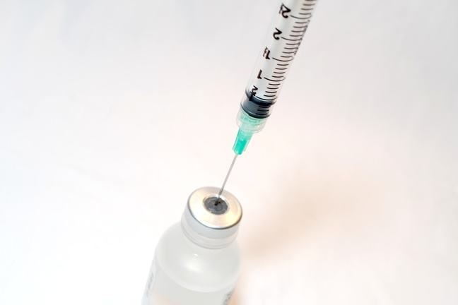 syringe going into vaccine bottle
