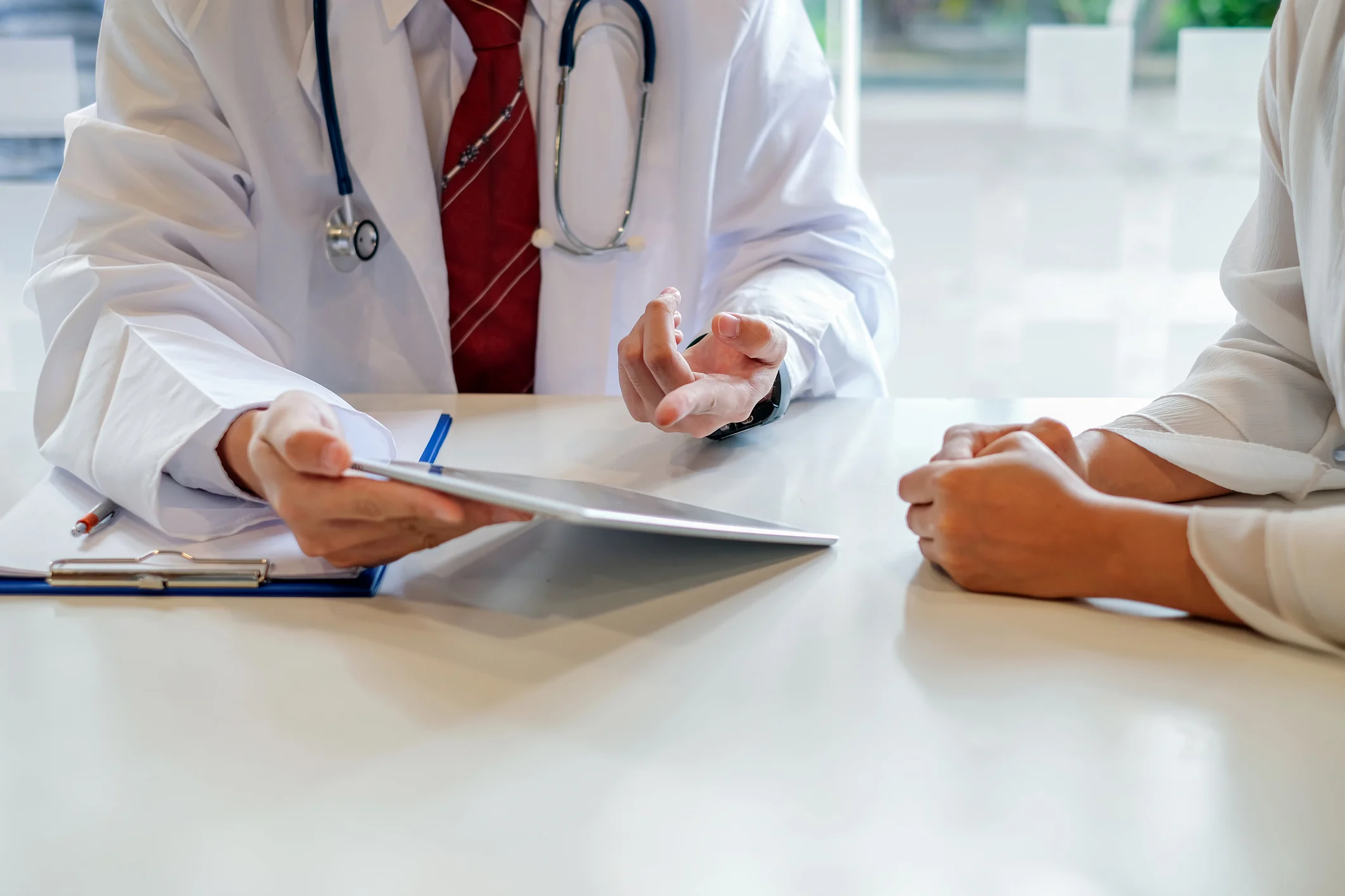 Doctor and female patient discussing while using digital tablet at hospital