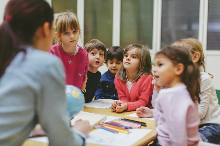 a teacher and younger students gathered together