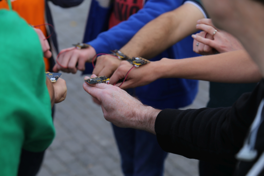 Hands in a circle holding Microbits