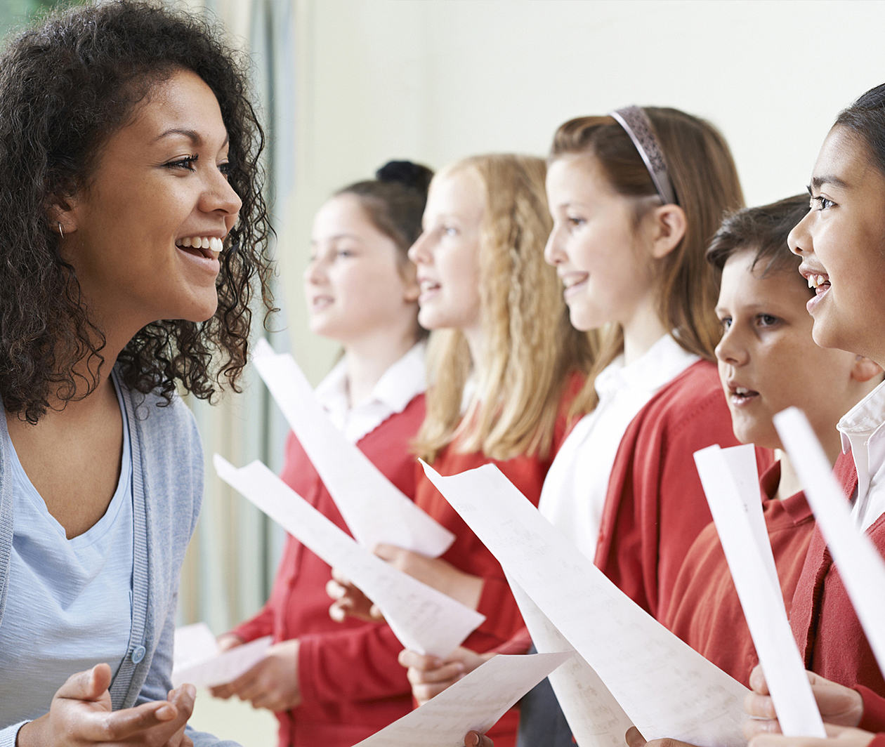 Children In School Choir Being Encouraged By Teacher