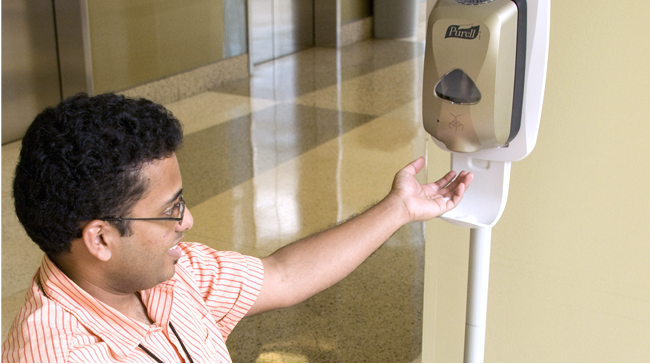 Healthcare worker with hand raised to obtain hand cleansing lotion from dispenser