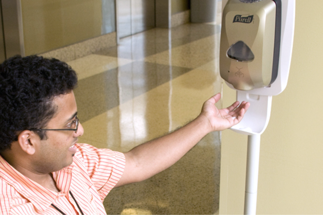 Healthcare worker with hand raised to obtain hand cleansing lotion from dispenser