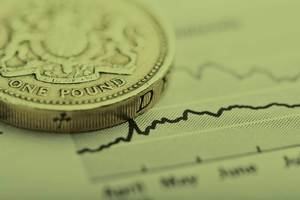 A coin sits on top of a line graph on a piece of paper – a metaphor for financial investments