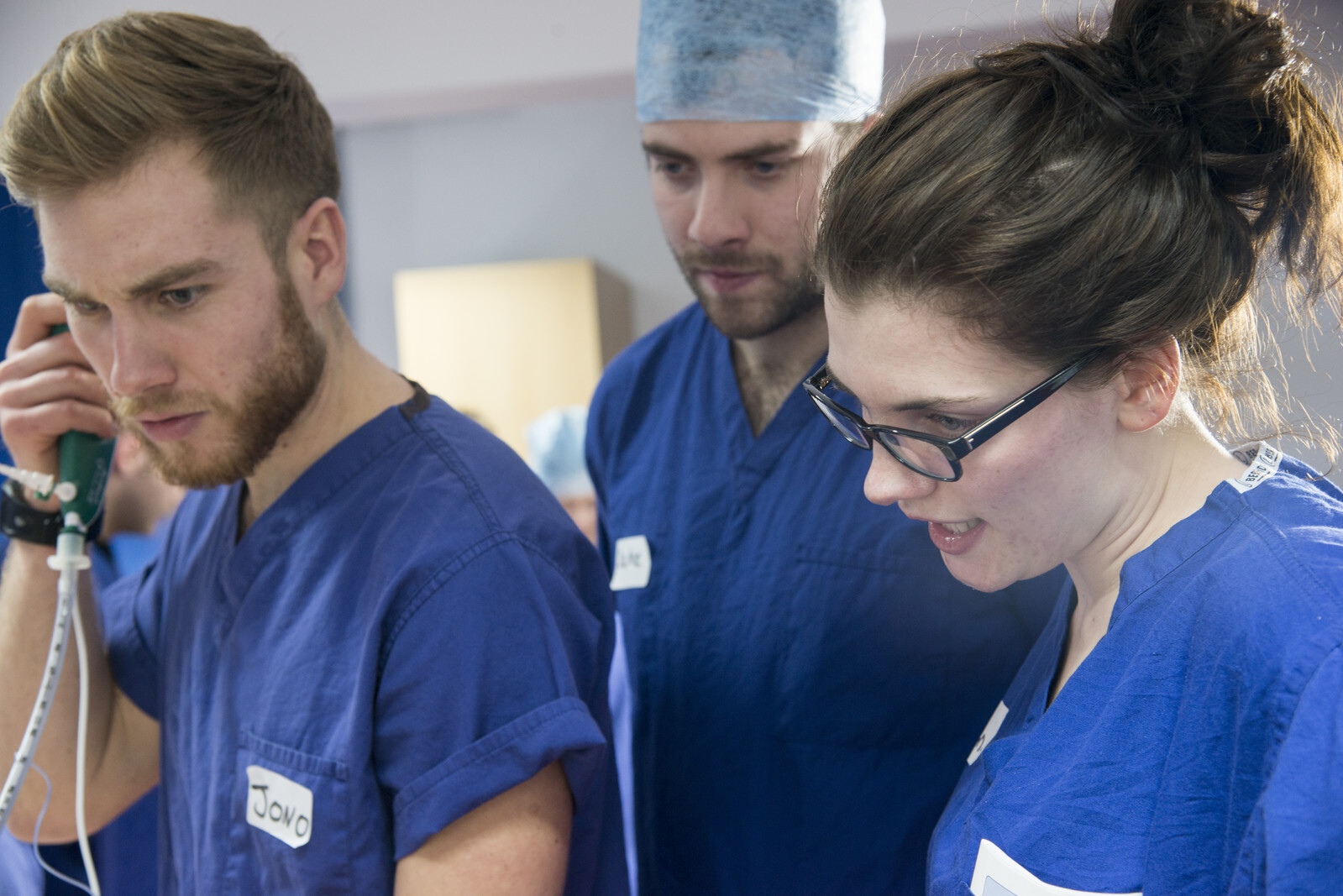 A group of three University of Leicester medical students wearing blue scrubs