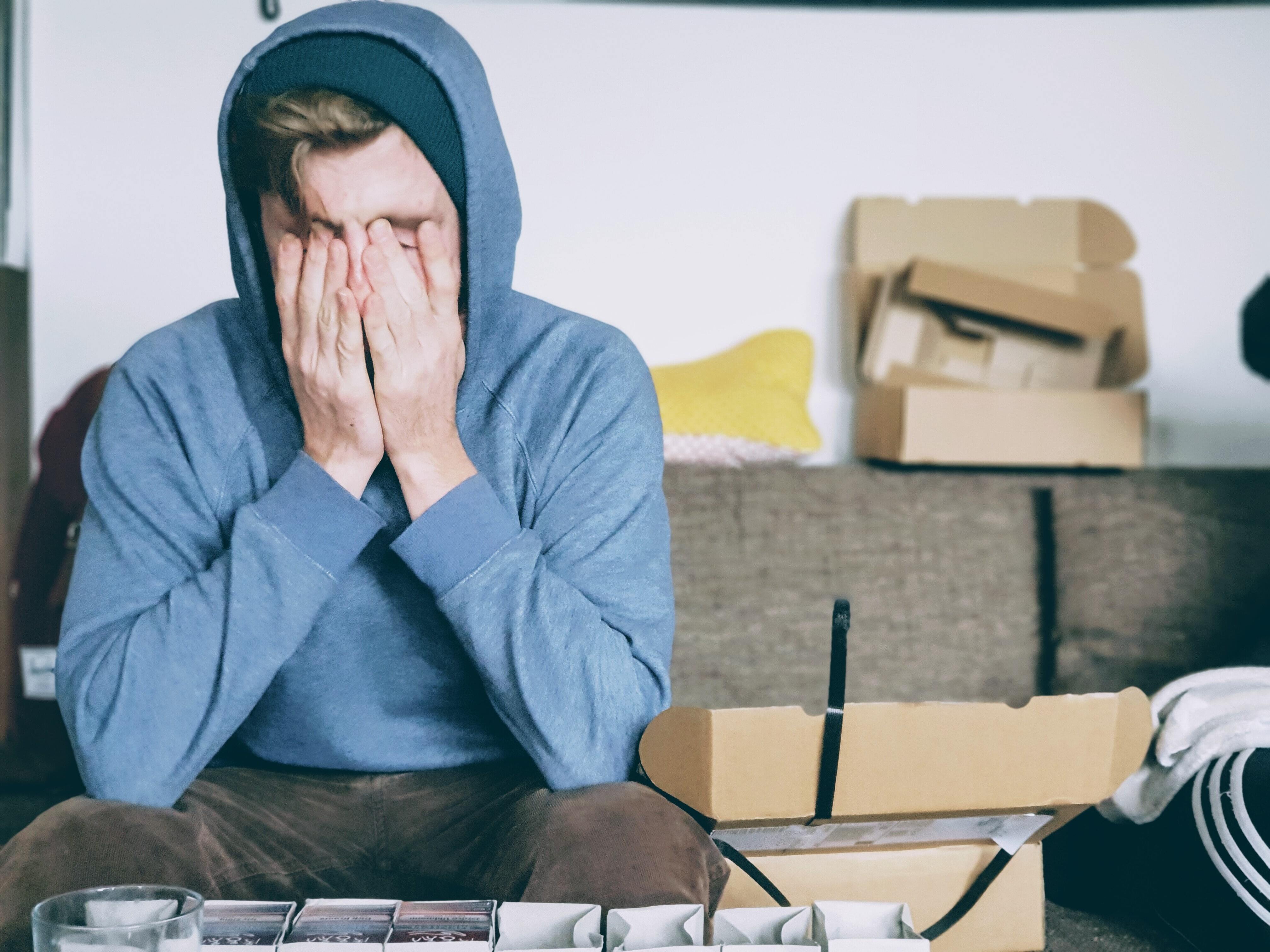 Man in a hoody with his face in his hands