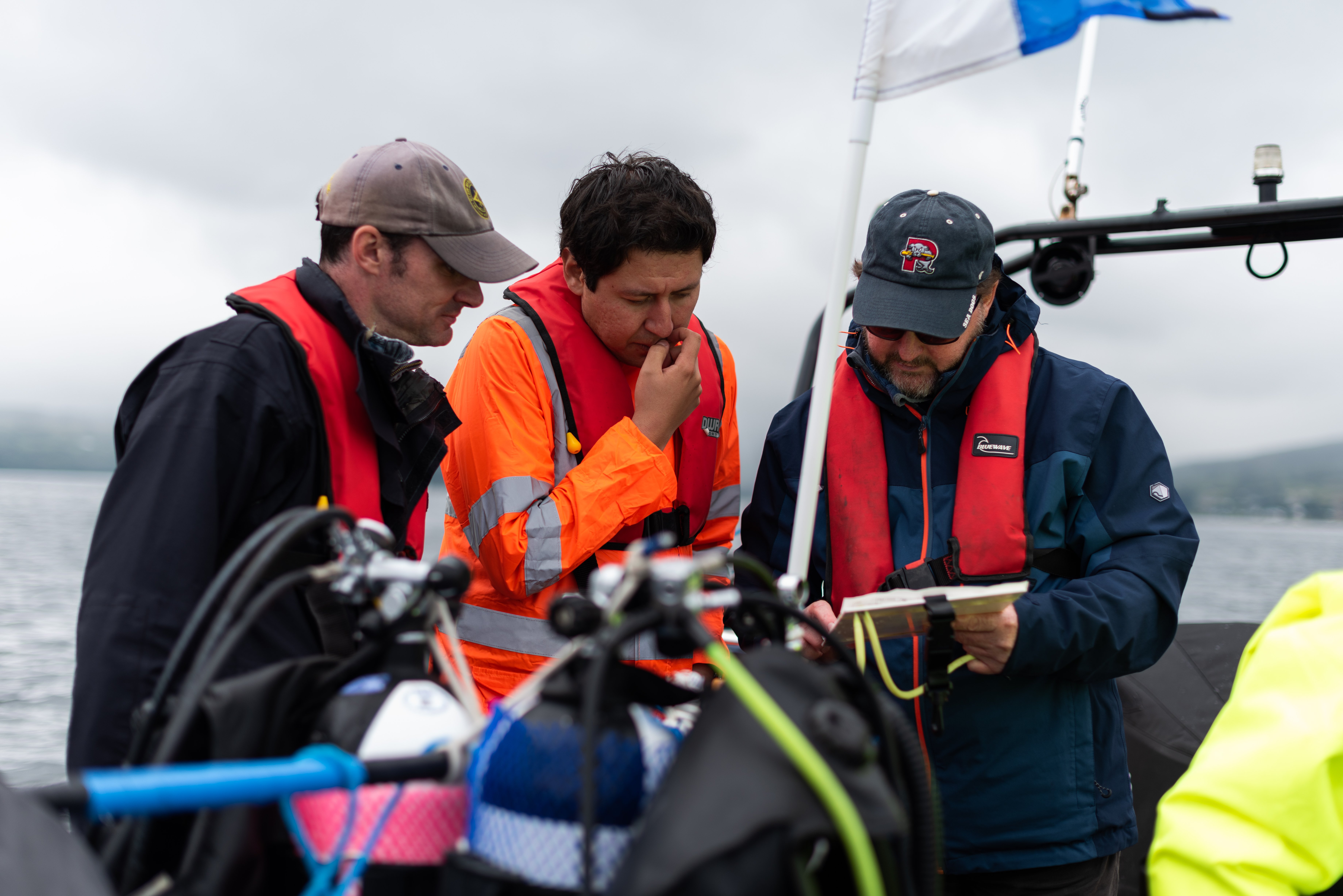 Three scientists on a boat looking at a clipboard