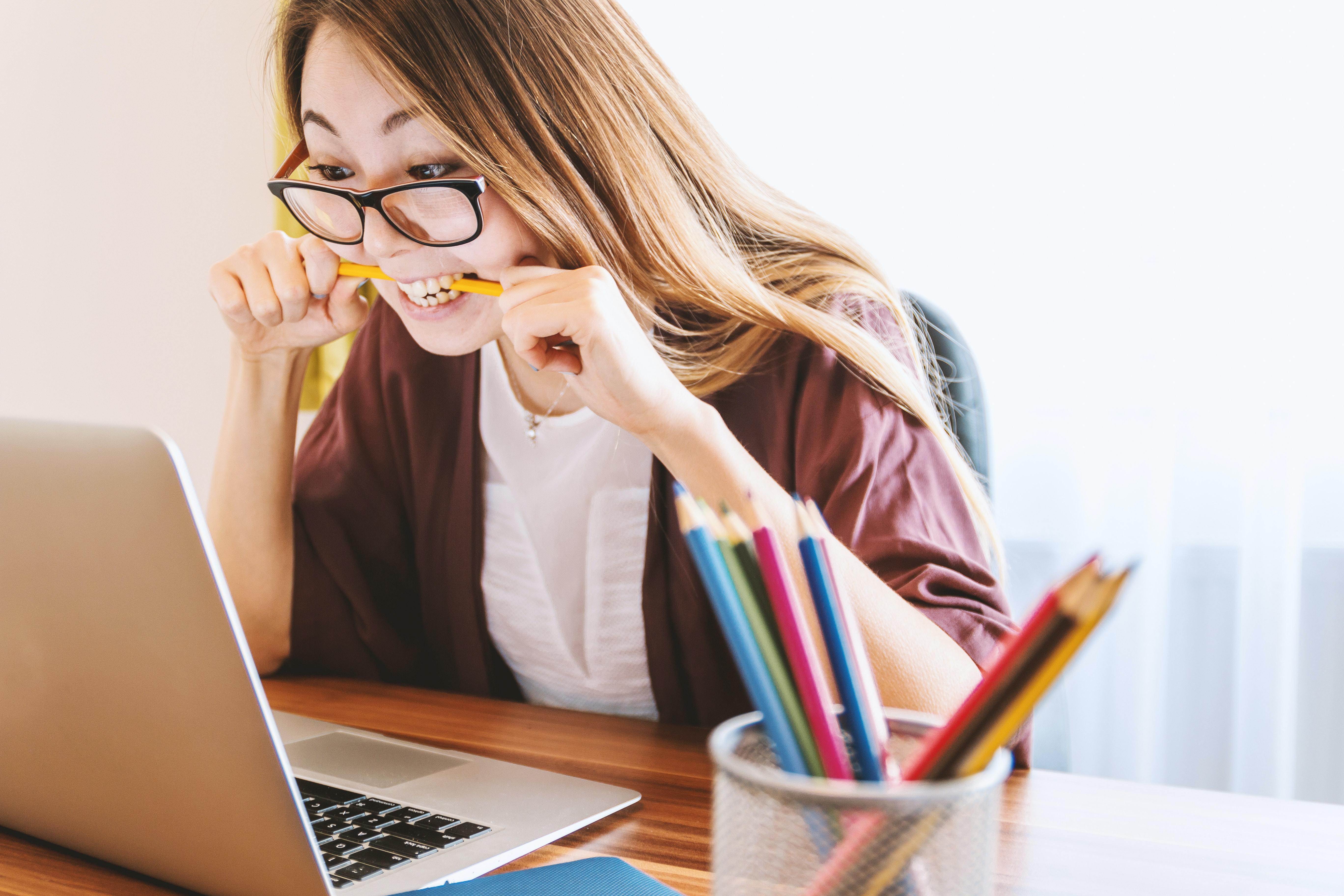 A young woman looking stressed while using a laptop