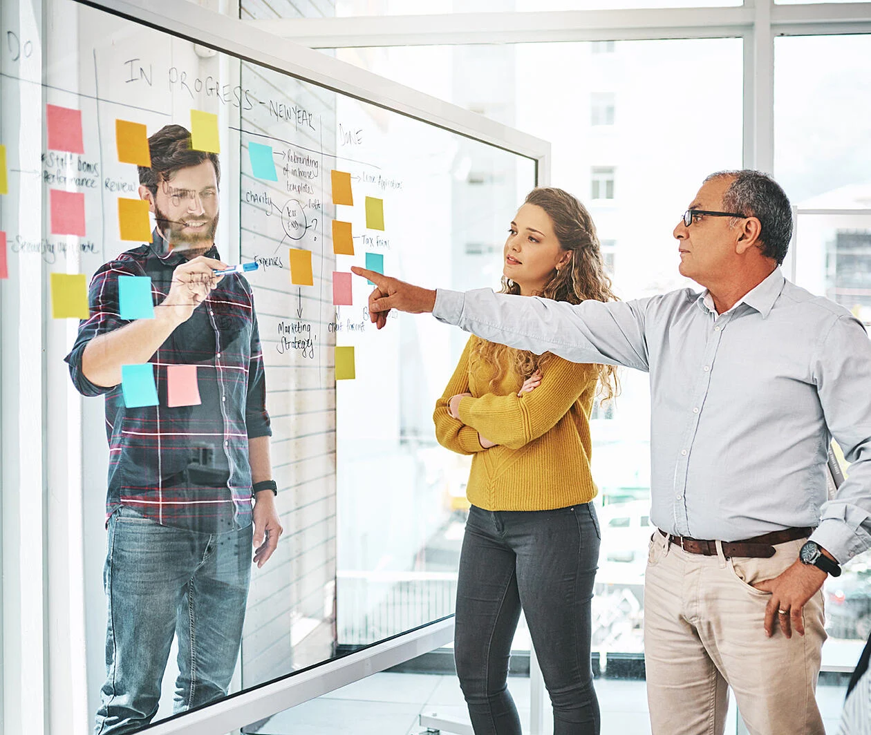 Some work colleagues using a clear board with post-its 