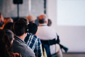 Man listening to lecture through hard of hearing headphones