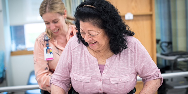 A picture of a lady being supported by a healthcare professional in hospital