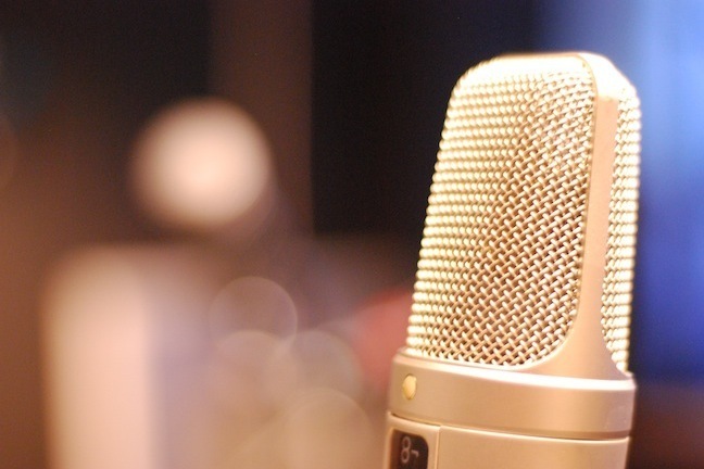 A modern silver microphone against a blurred blue background.