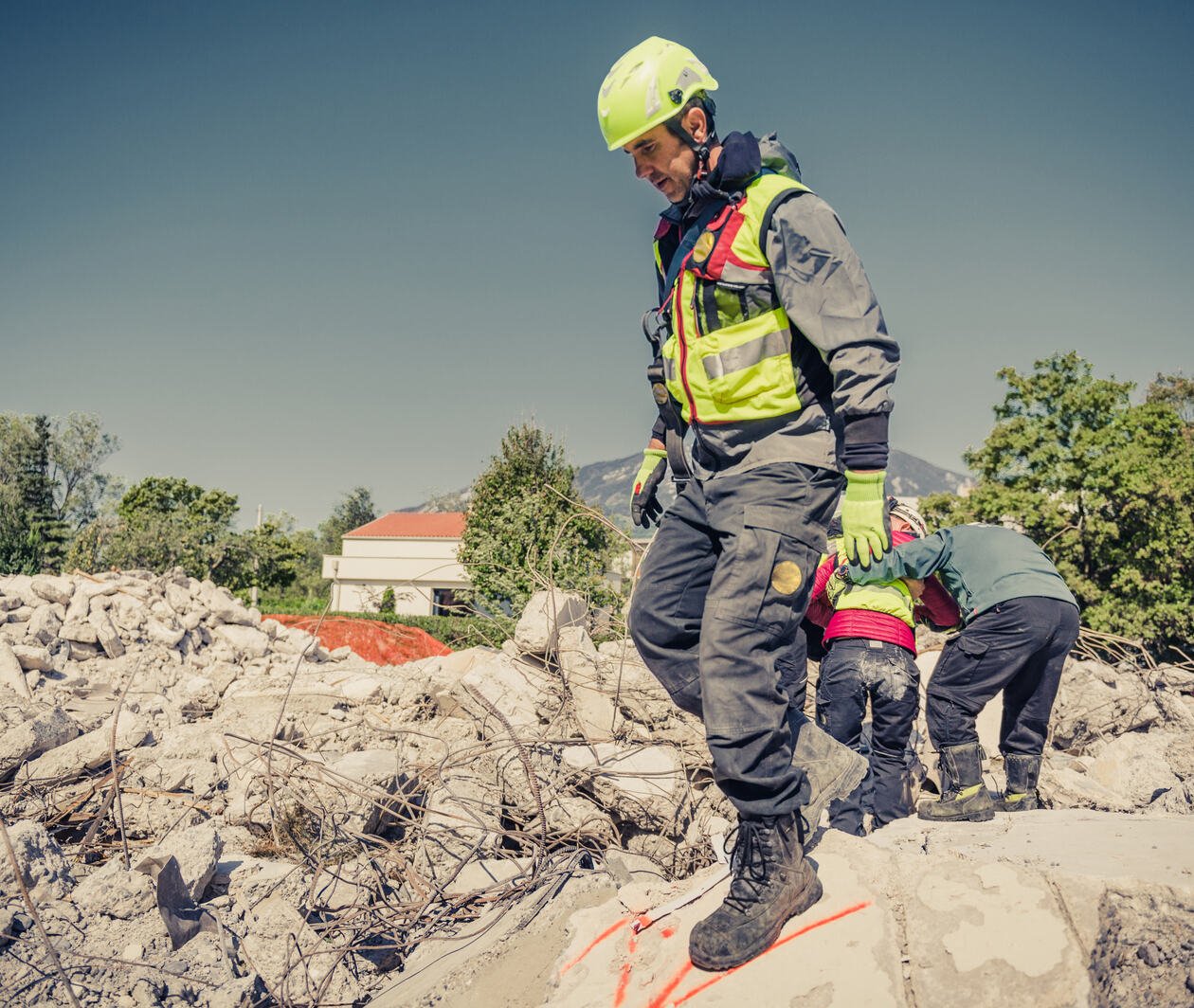 An emergency support officer standing on rubble