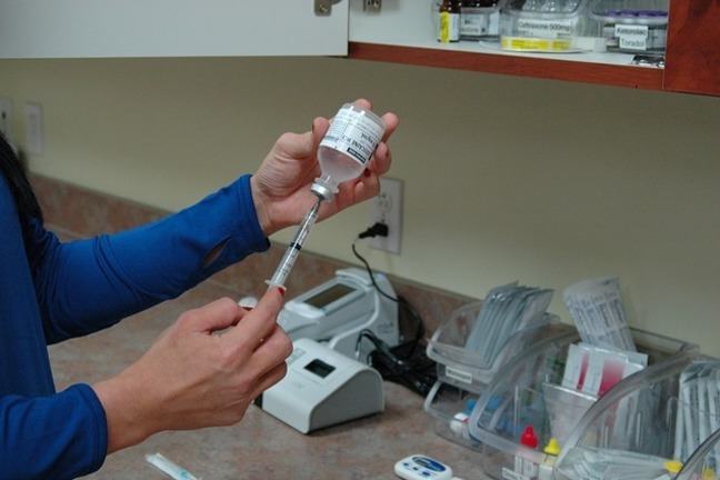 Close up of nurses hands drawing up an injection from a vial into a syringe