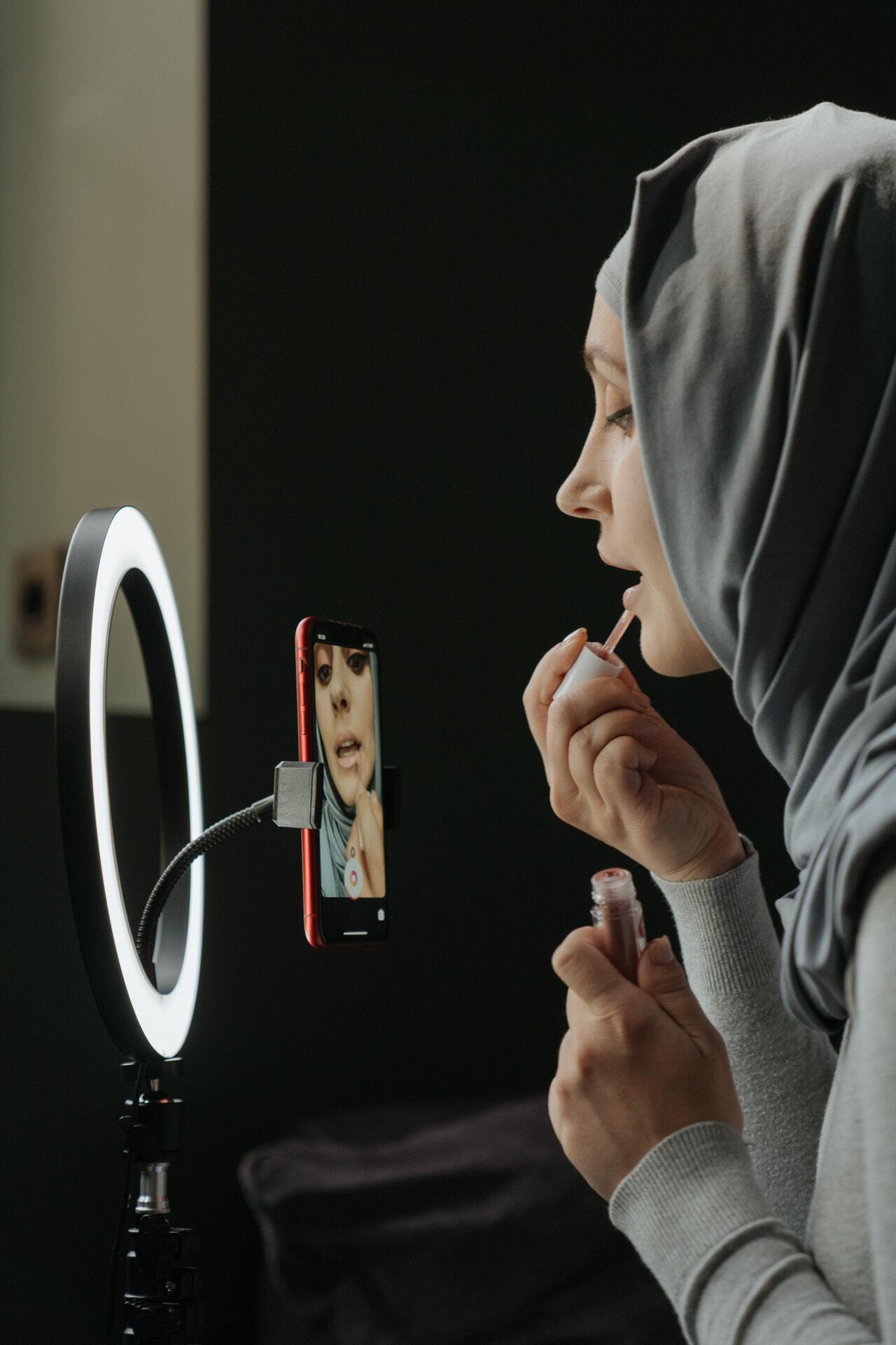 woman doing her makeup in front of a phone