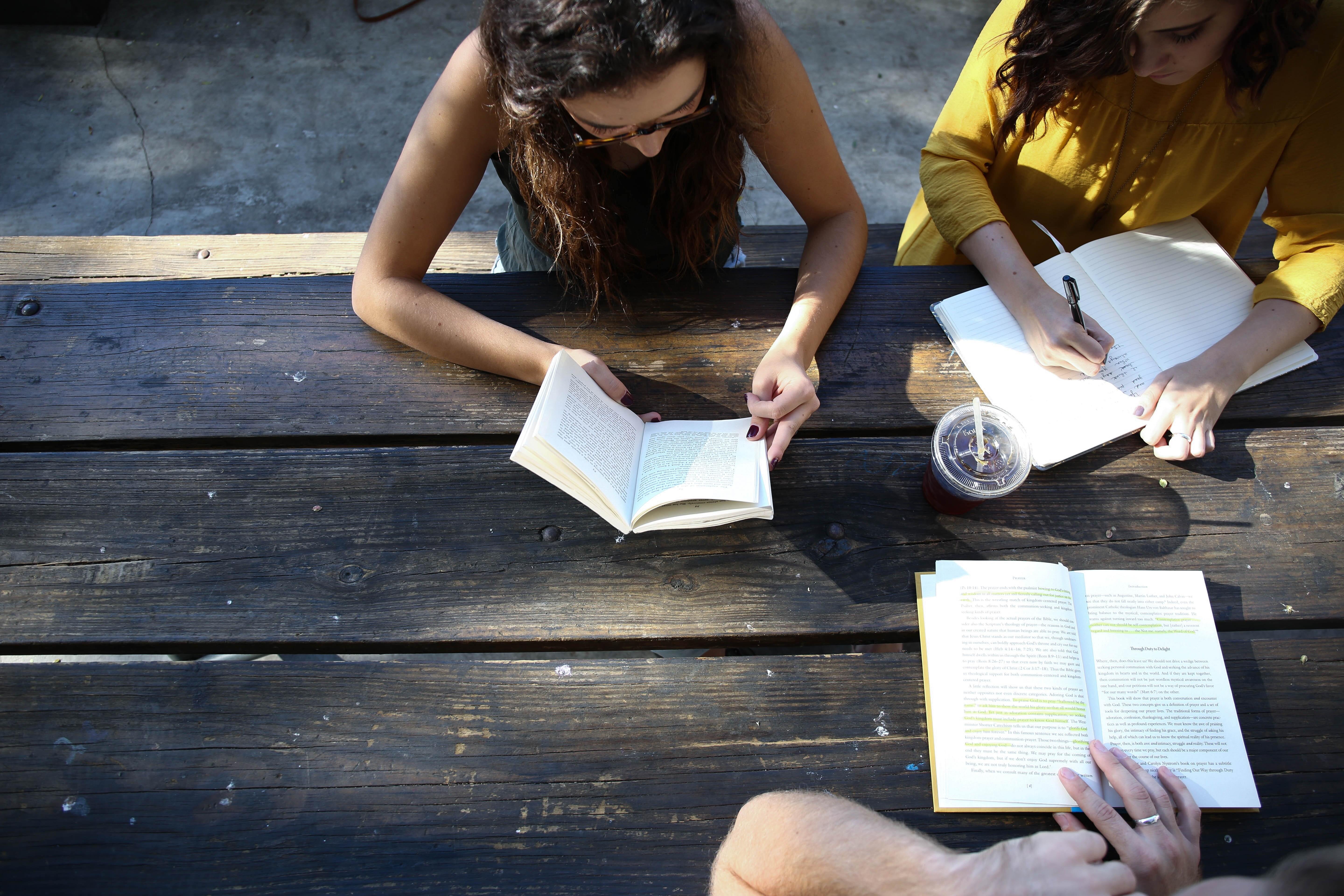 Woman and others look over their books whilst sitting at a table