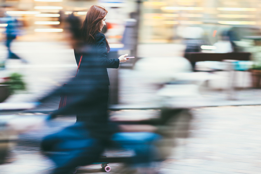 woman ride a skateboard while looking at mobile phone