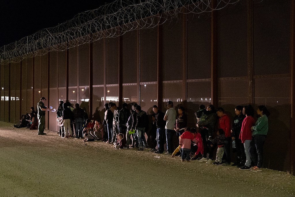 People queuing up at a border wall between Mexico and the US