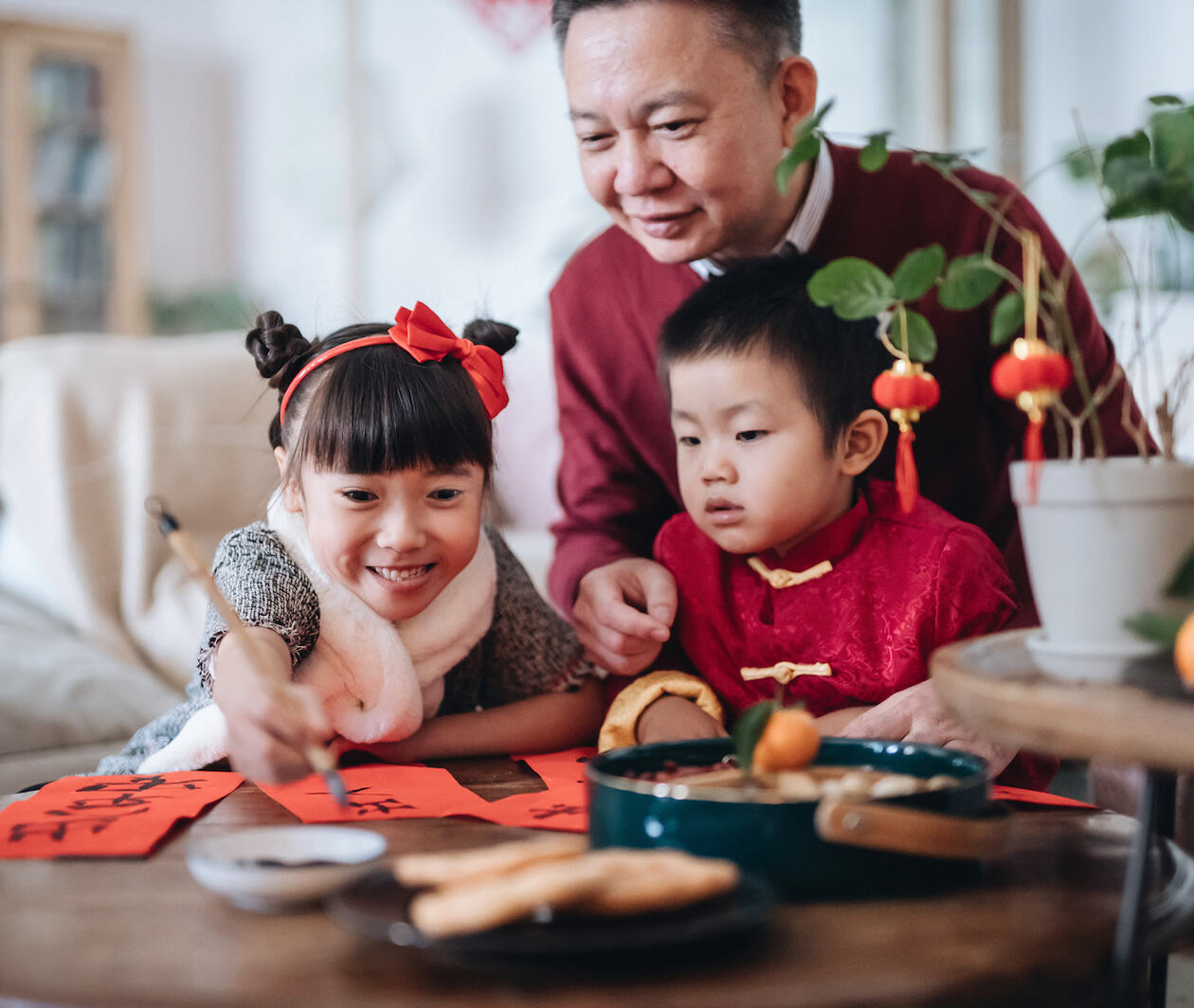 A Chinese father teaching his young son and daughter traditional Chinese calligraphy 