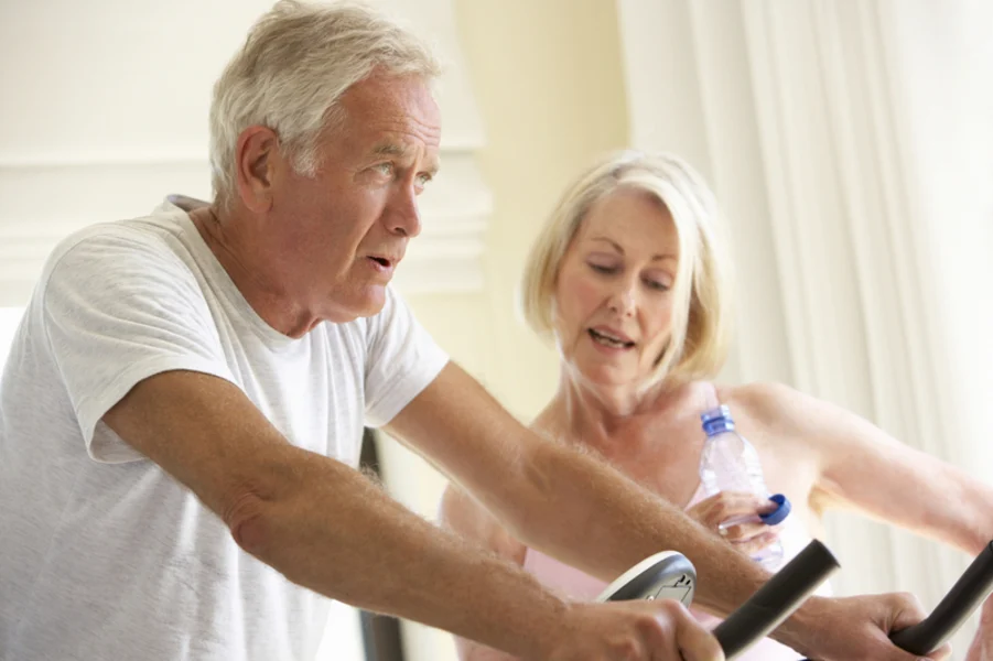 A man sitting on a cycle trainer with a woman looking on.